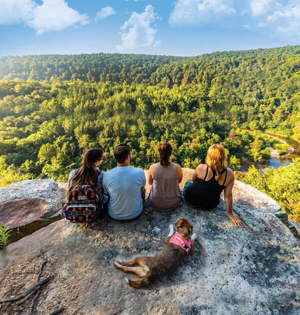 people sitting on a mountain with their dog